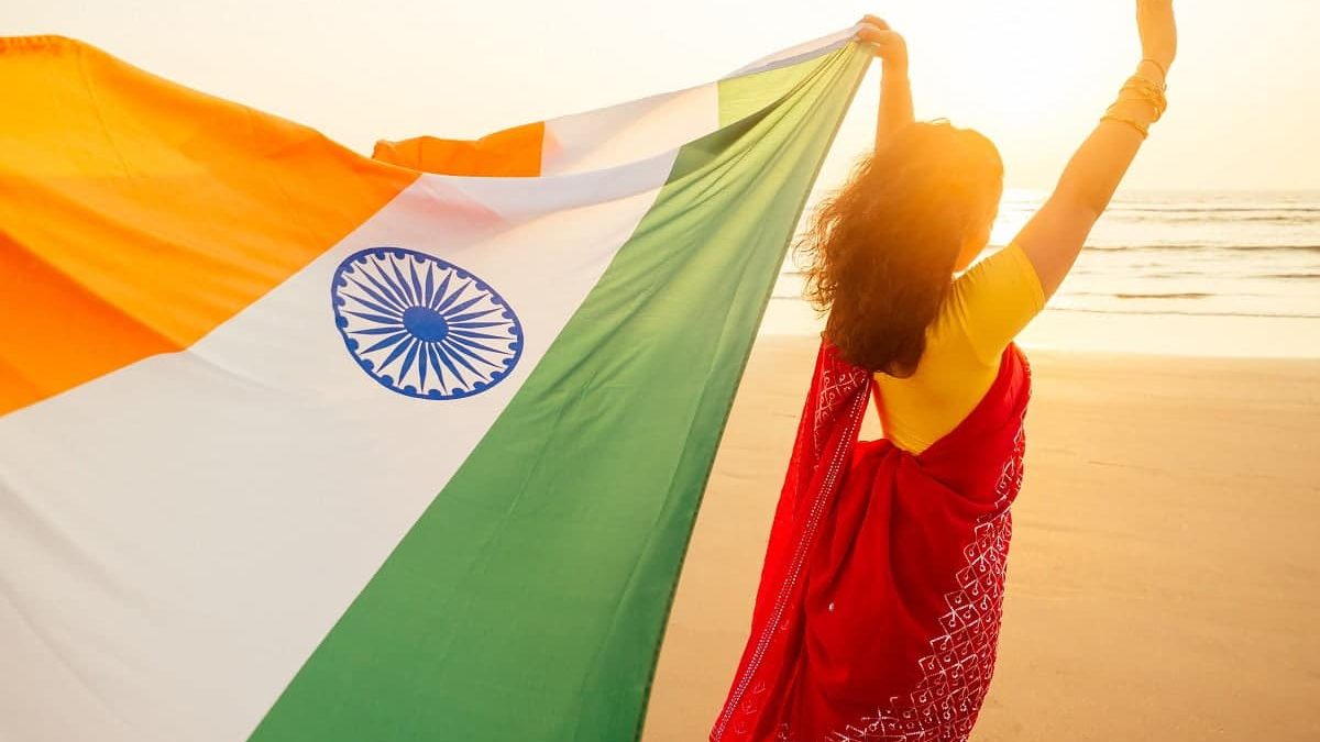 beautuful woman holding Indian flag tricolour ,wearing red tradition sari on sea beach in Goa.