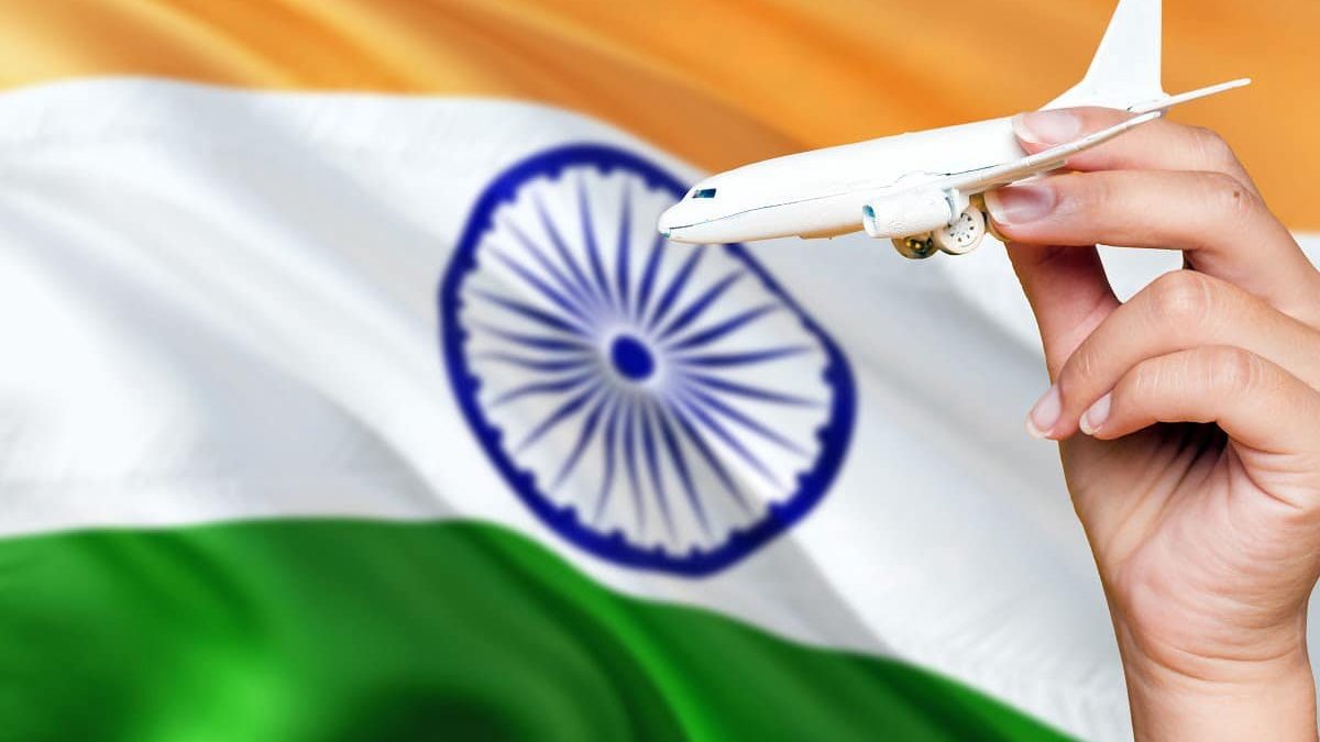 India travel concept. Woman holding a miniature plane on national flag background. Holiday and voyage theme with copy space for text.