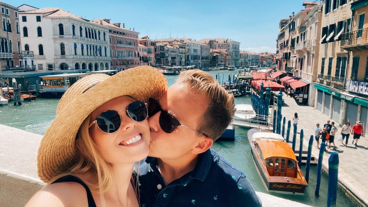 Man kisses woman on cheek in front of Grand Canal in Venice