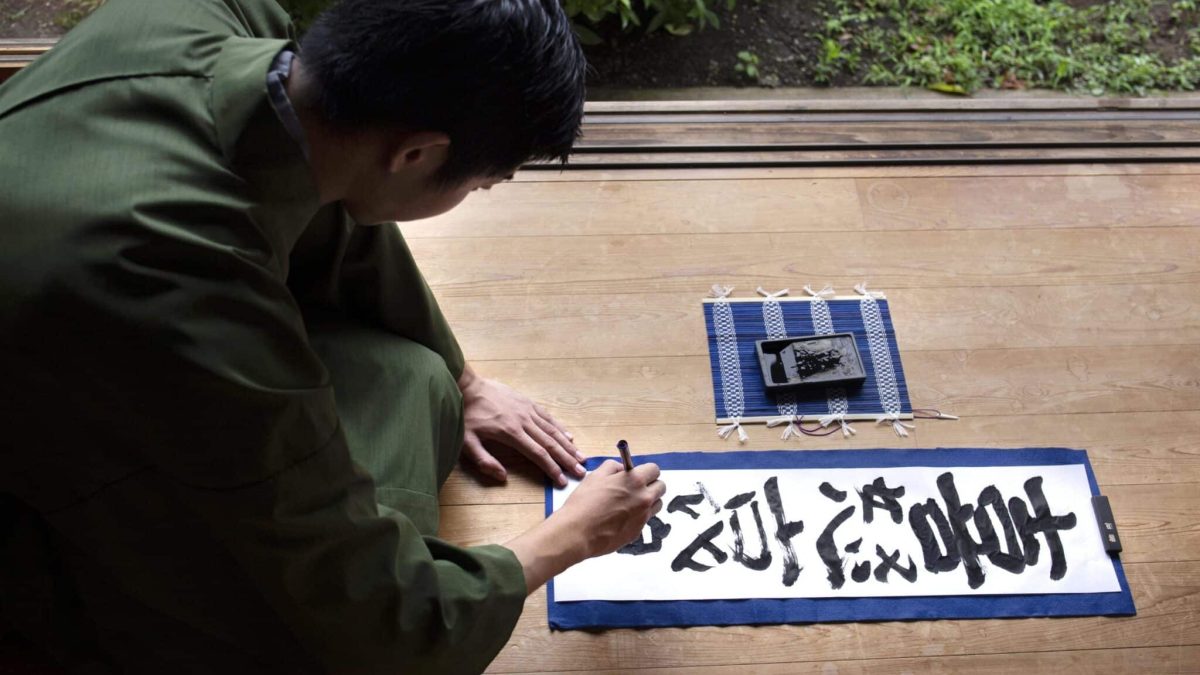 man-practicing-japanese-handwriting-with-brush-ink